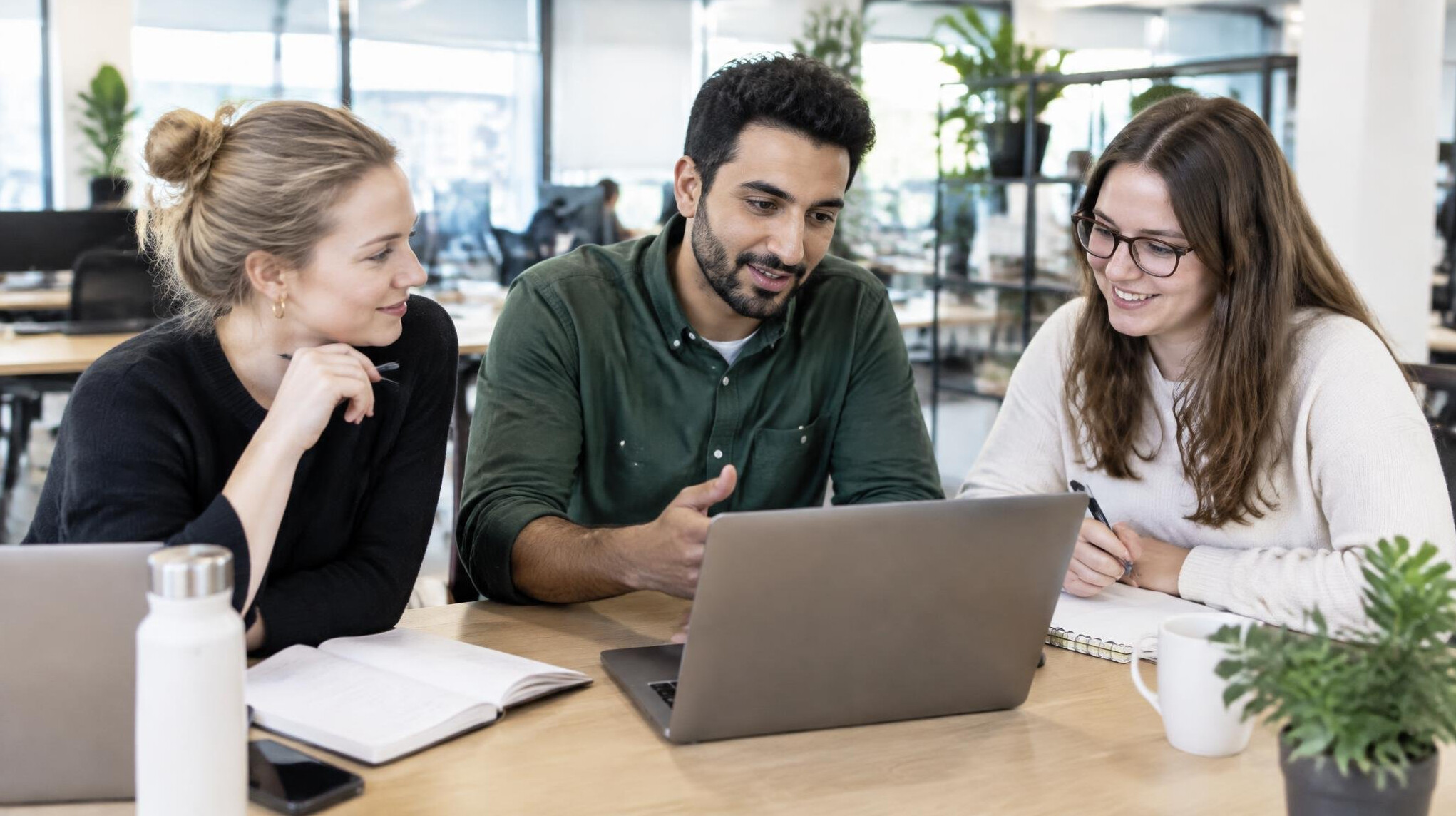 Colleagues collaborating around a table with laptops