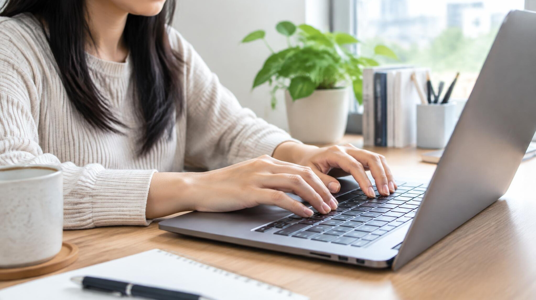 Close up of hands typing on a laptop keyboard at home